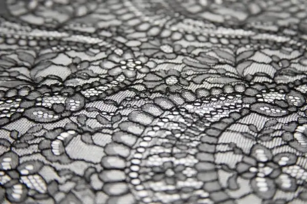 A close-up of delicate, high-end white Leavers lace fabric.