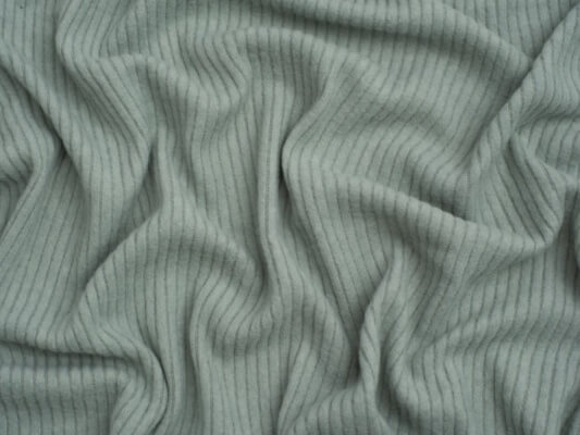 Eine Nahaufnahme eines Dessous-Kleidungsstücks aus einem weichen, gebürsteten gerippten Strickstoff in einem warmen, neutralen Ton.