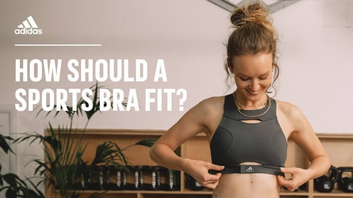 A woman performing a simple "arms up" test to check the fit of her sports bra's bottom band.